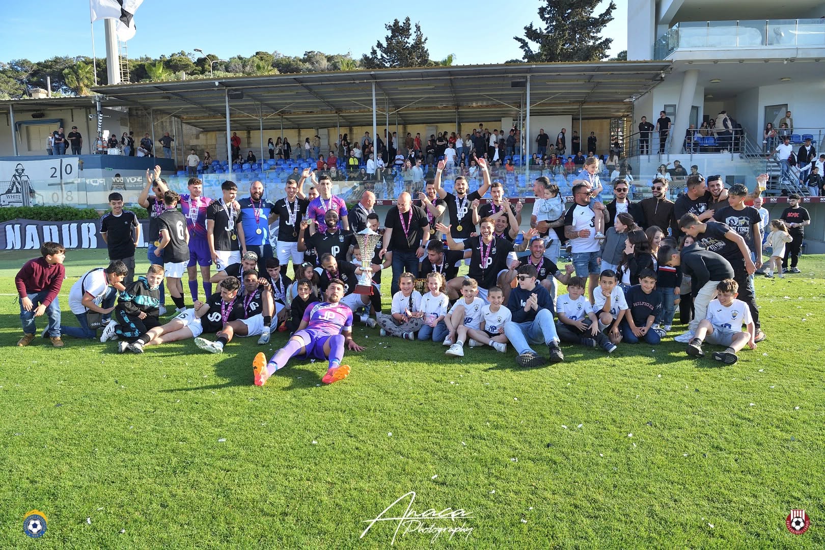 Nadur Youngsters squad and supporters celebrating with a trophy